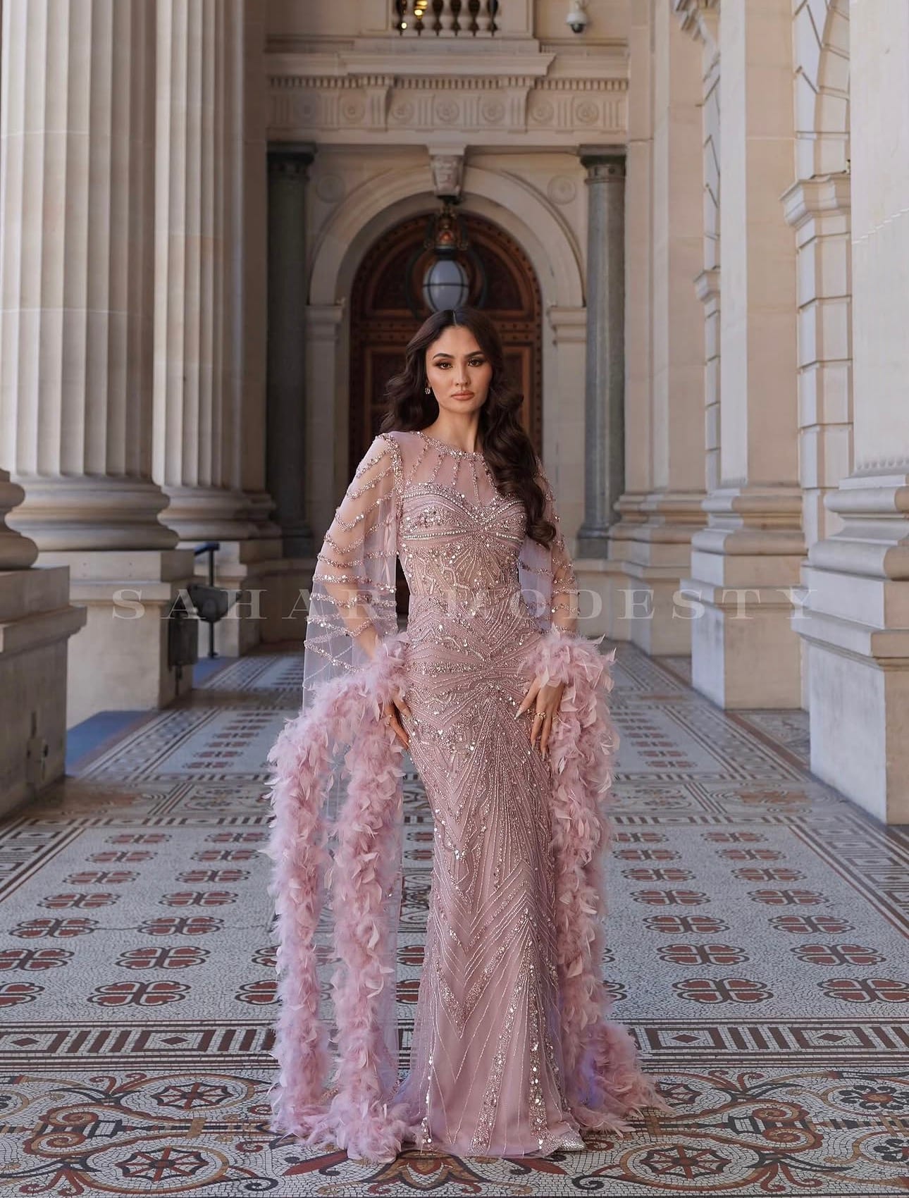 Sahar Modesty blush crystal modest bridal gown photographed in an architectural hallway.