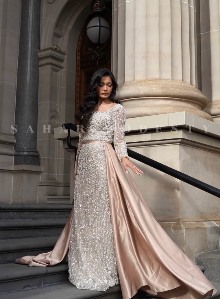 Champagne pearl modest gown with satin overskirt on stone steps.